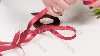 假日装饰品。 手从<strong>桌子上拿起</strong>粉红色的丝带。 白色的。 关门